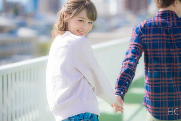 彼氏に手を引かれて振り返る彼女